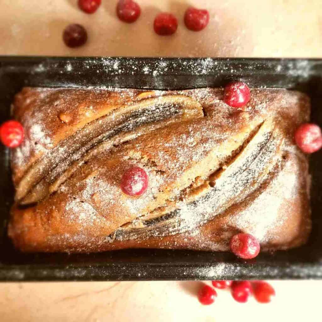 Cherry banana bread in the baking bread tin with cherries on top.