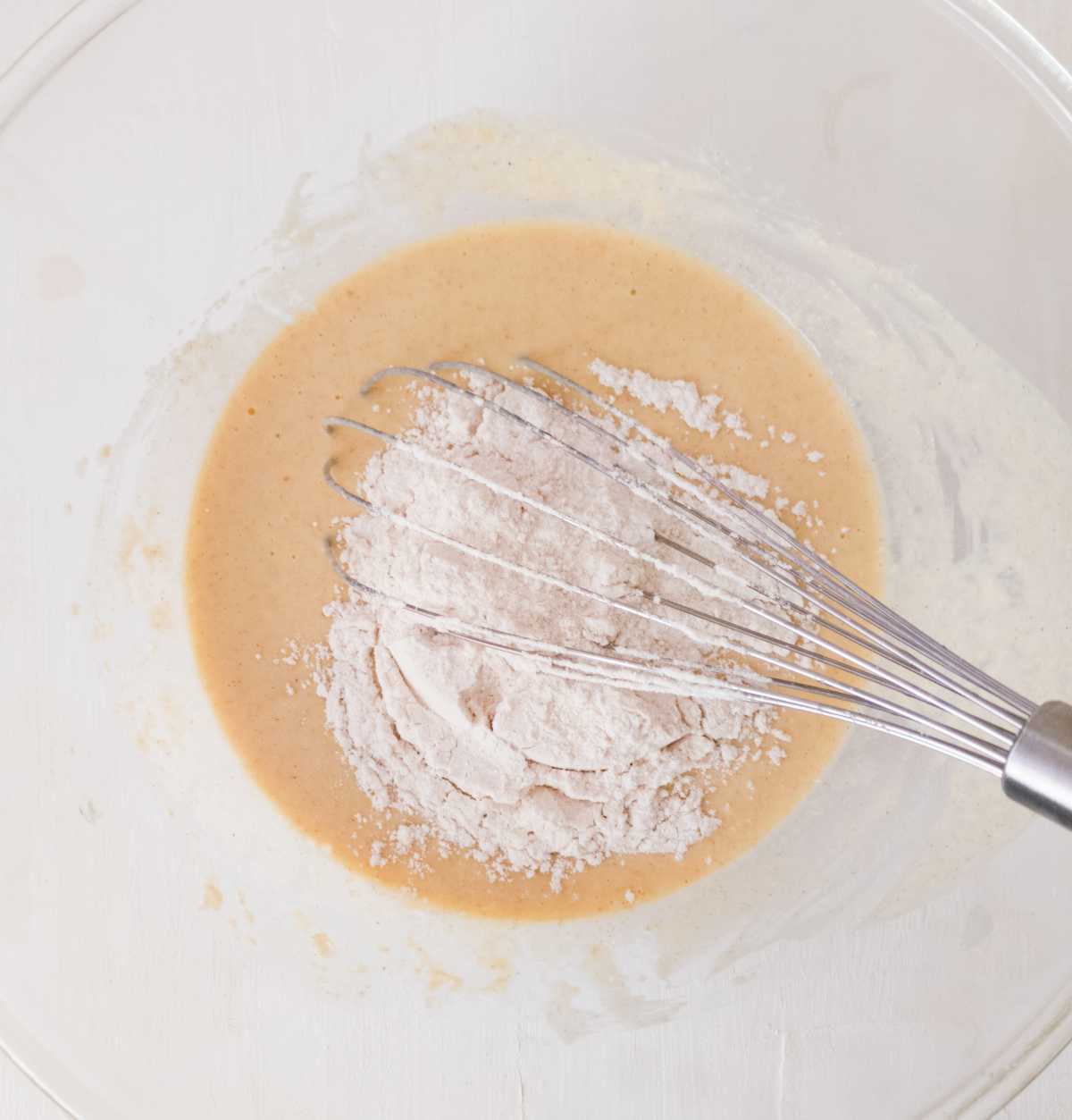 Dry ingredients in the bowl with wet ingredients and a whisk.