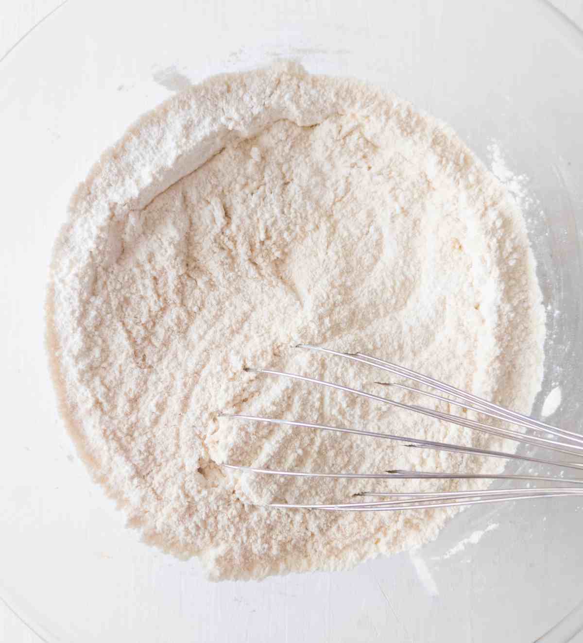 Dry ingredients mixed in a large mixing bowl with a whisk.