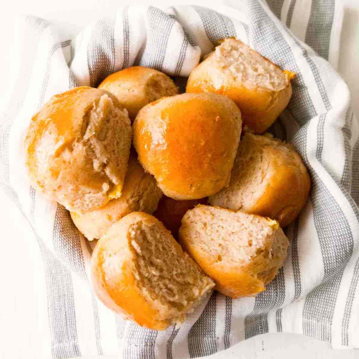 Gluten-free sourdough rolls on a kitchen towel in a bowl.