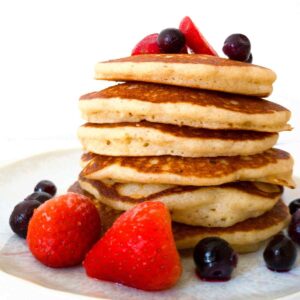 Gluten-free sourdough discard pancakes stacked with strawberries and blueberries.