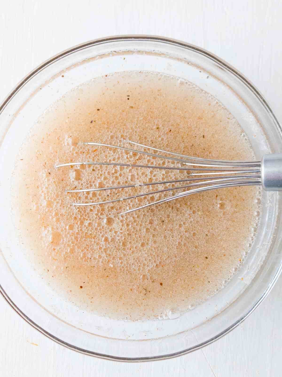 Psyllium husk mixed with water in a glass bowl and a whisk.