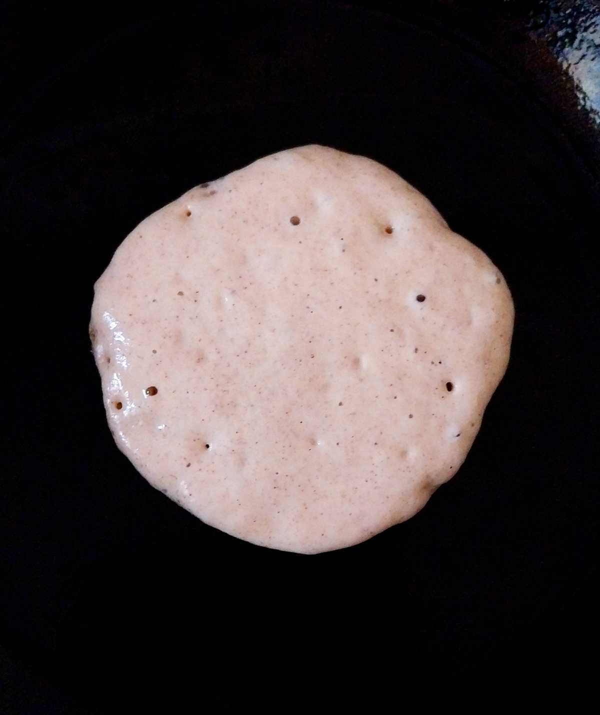 Pancake batter on a cast iron pan.