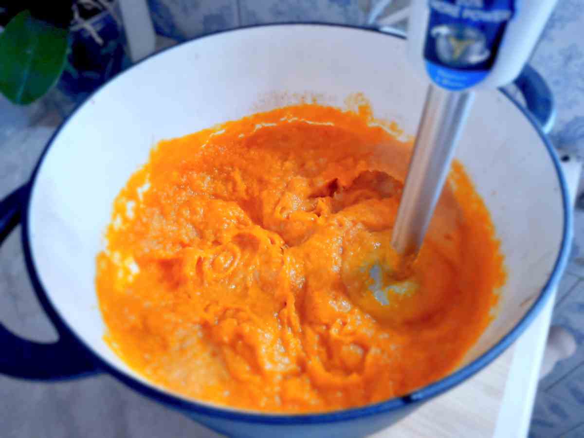 Blending the pumpkin soup with an immersion blender.