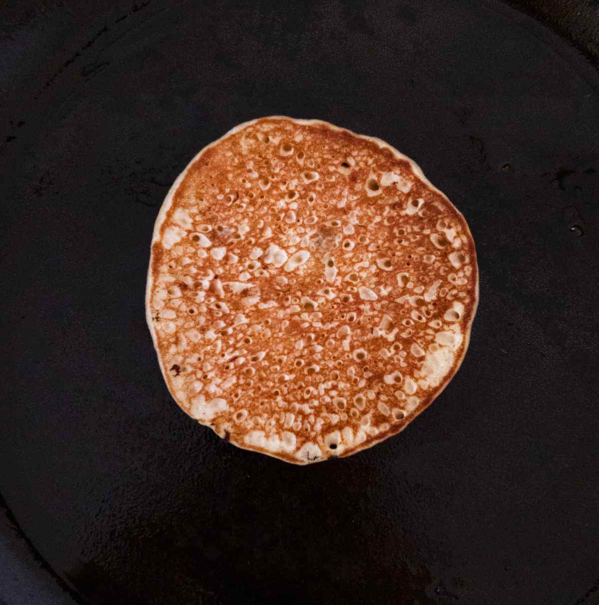 Flipped pancake on a cast iron skillet.
