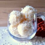 Homemade Raffaello balls in a glass with almonds in the background.