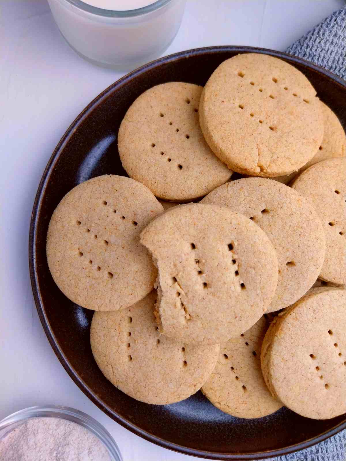 Buckwheat shortbread cookies on a plate with a glass of milk in the background.