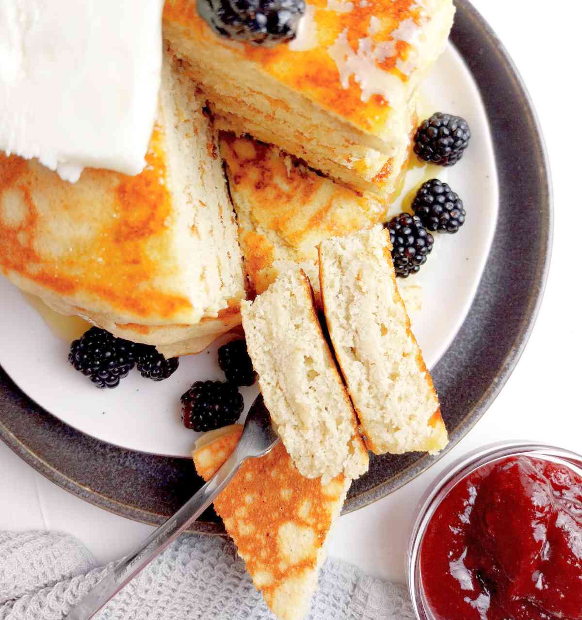 Finished pancakes on a plate with blackberries and jam.