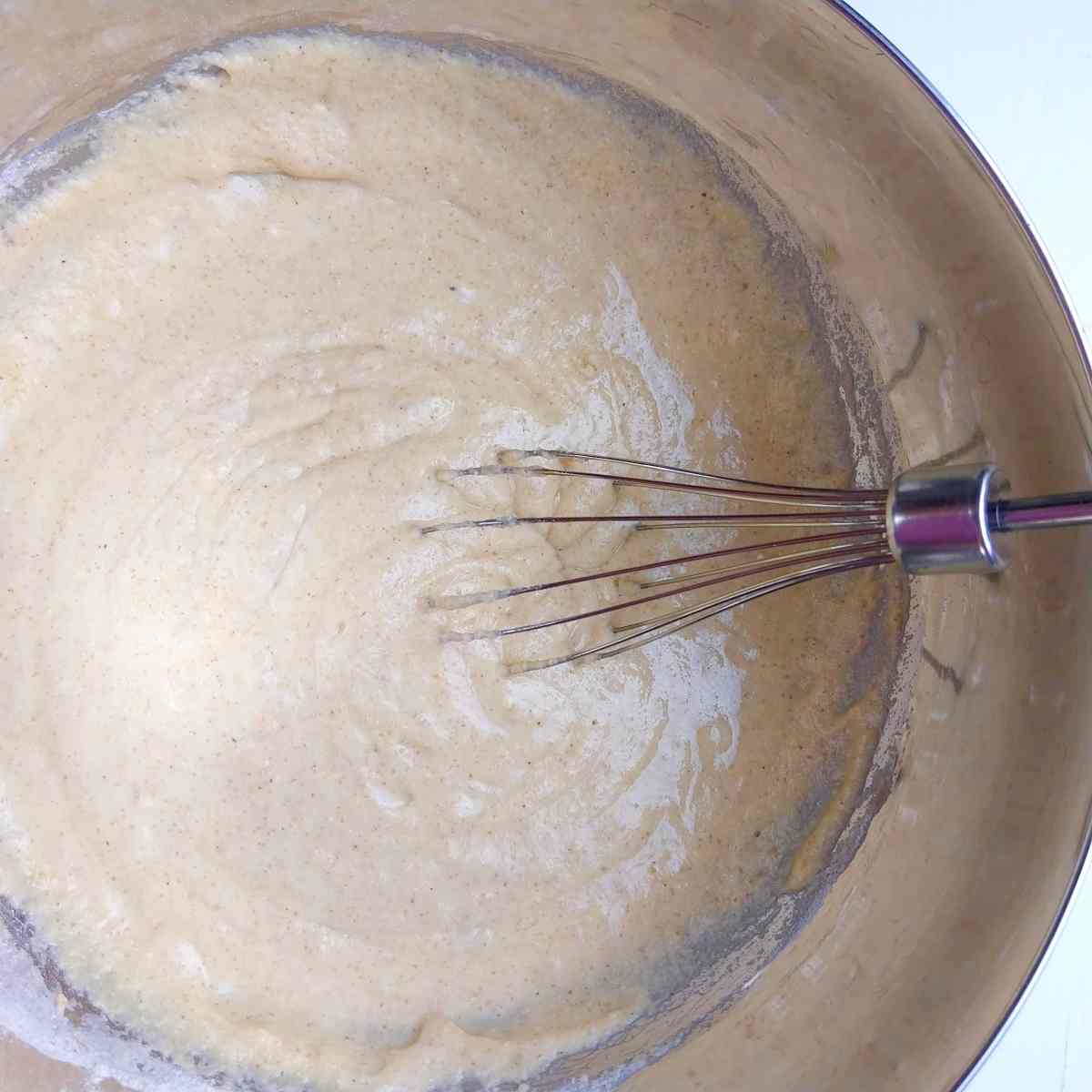 Buckwheat pancake batter in a metal mixing bowl with a whisk.