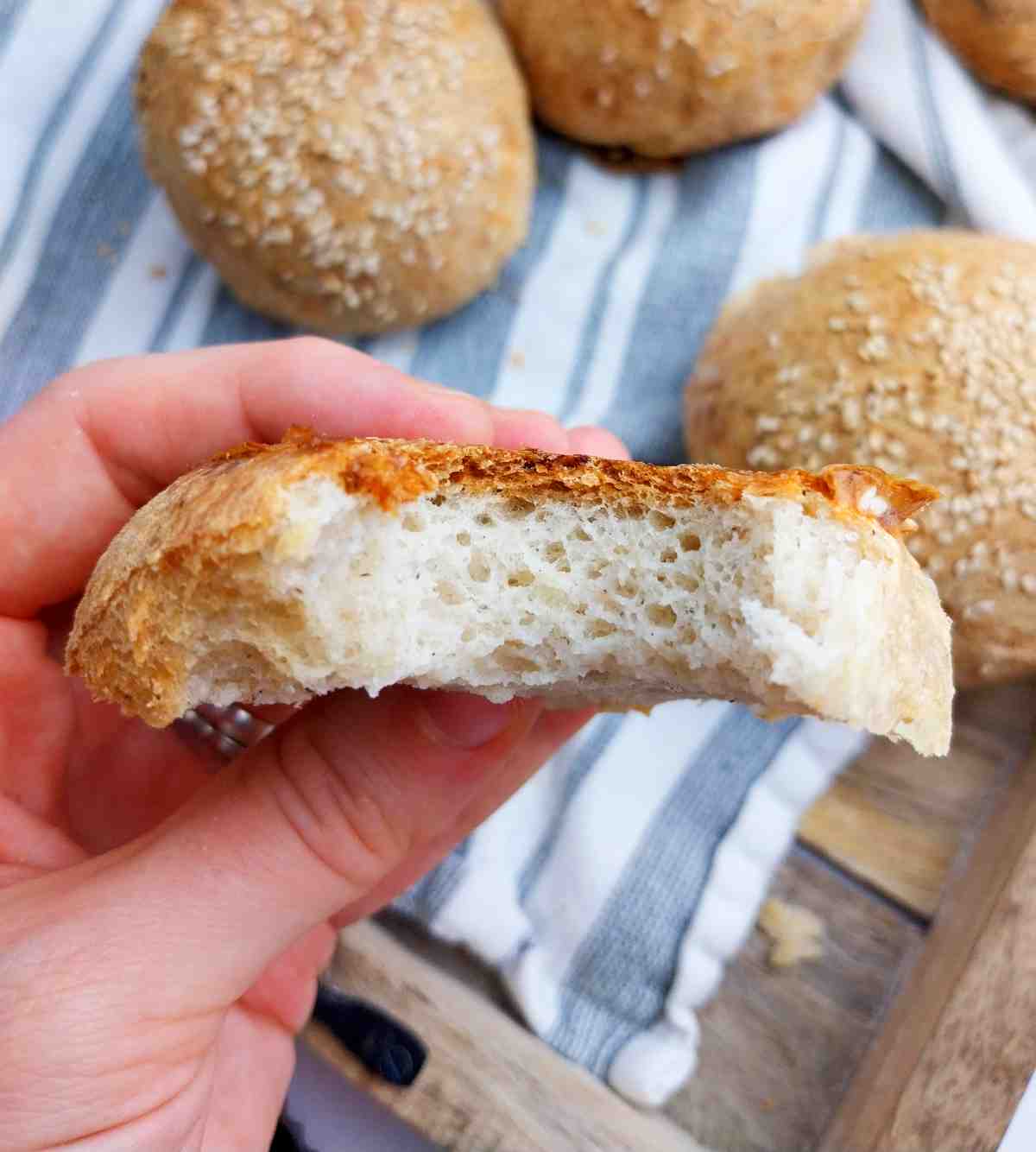 A burger bun bit into and held by a hand.