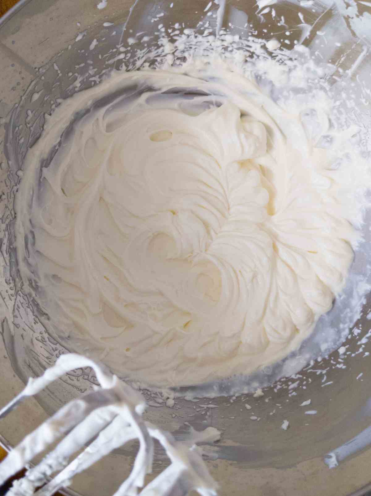 Cream cheese frosting whipped in a metal mixing bowl.