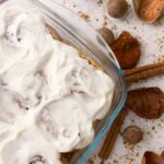 Gluten-free sourdough cinnamon rolls in a baking dish with frosting on top.
