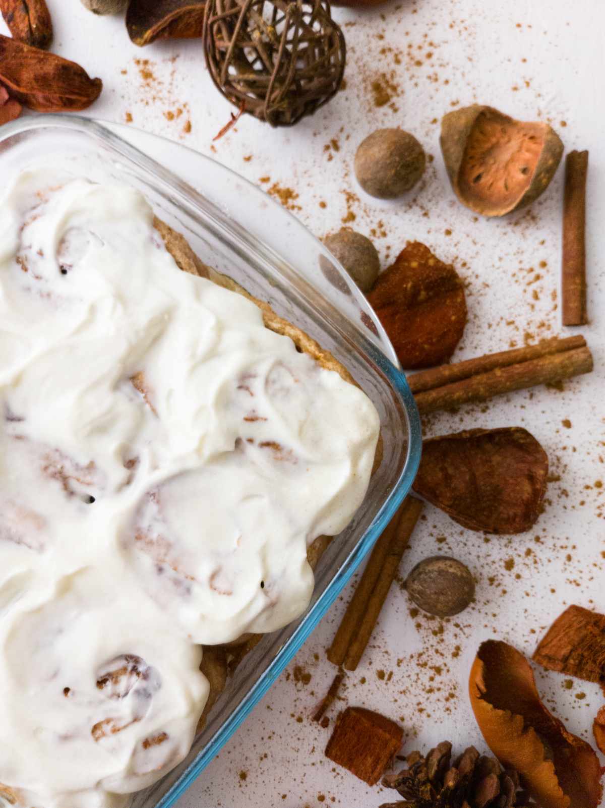 Gluten-free sourdough cinnamon rolls in a dish with frosting.