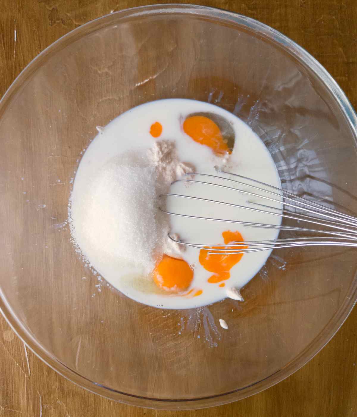 Wet ingredients combined in a large mixing bowl with a whisk.