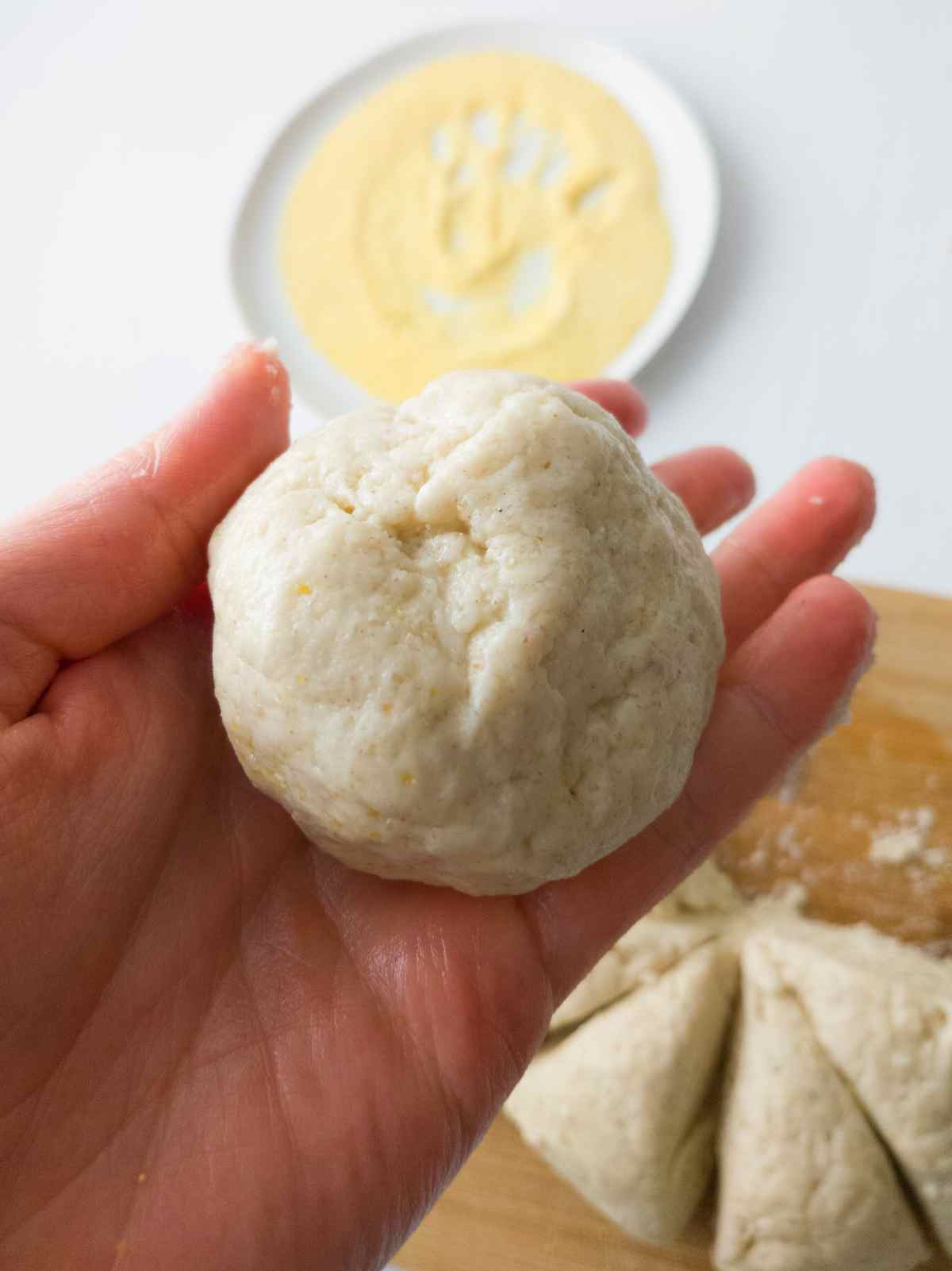 English muffins shaped into a ball held by a hand.