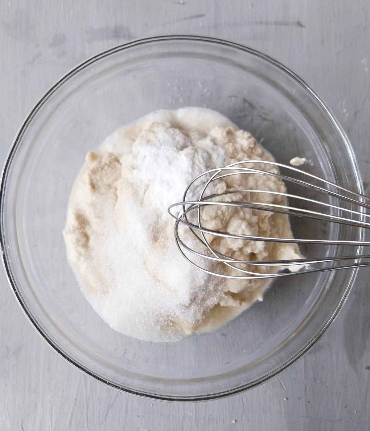 Ingredients in a glass bowl with a whisk.