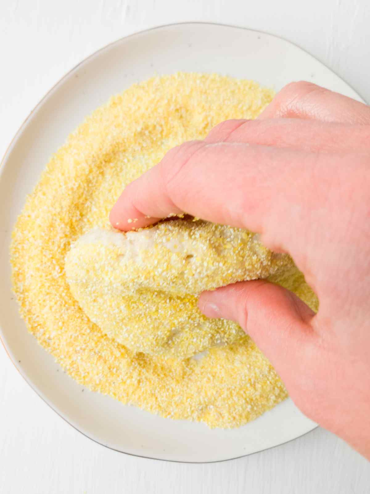 Dipping a muffin disc in cornmeal.