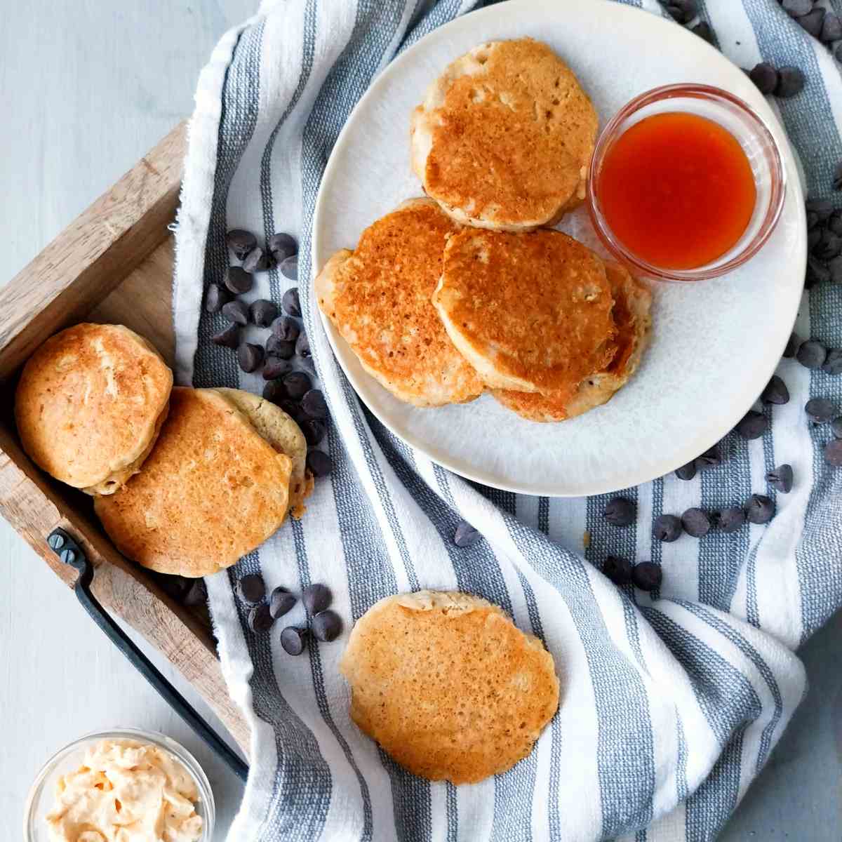 gluten-free sourdough crumpets on a wooden tray lined with a kitchen towel and sprinkled with chocolate chips.