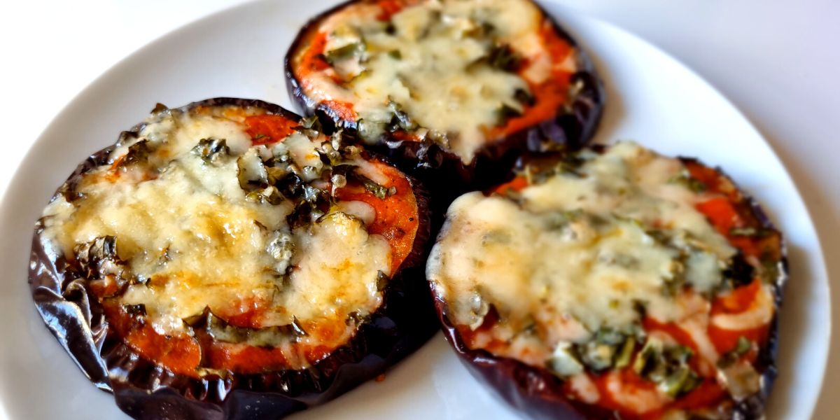 Three eggplant pizzas on a white plate.