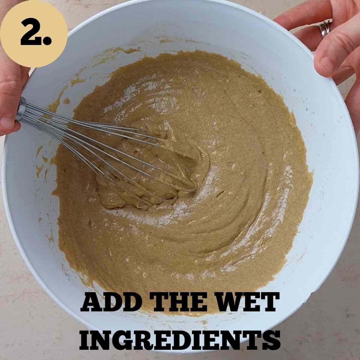 The muffin batter mixed in a white mixing bowl with a whisk.