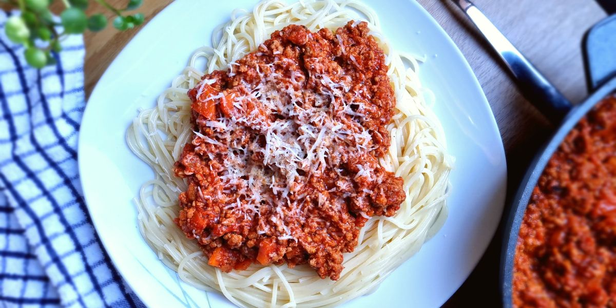 Spaghetti Bolognese on a plate with grated cheese.