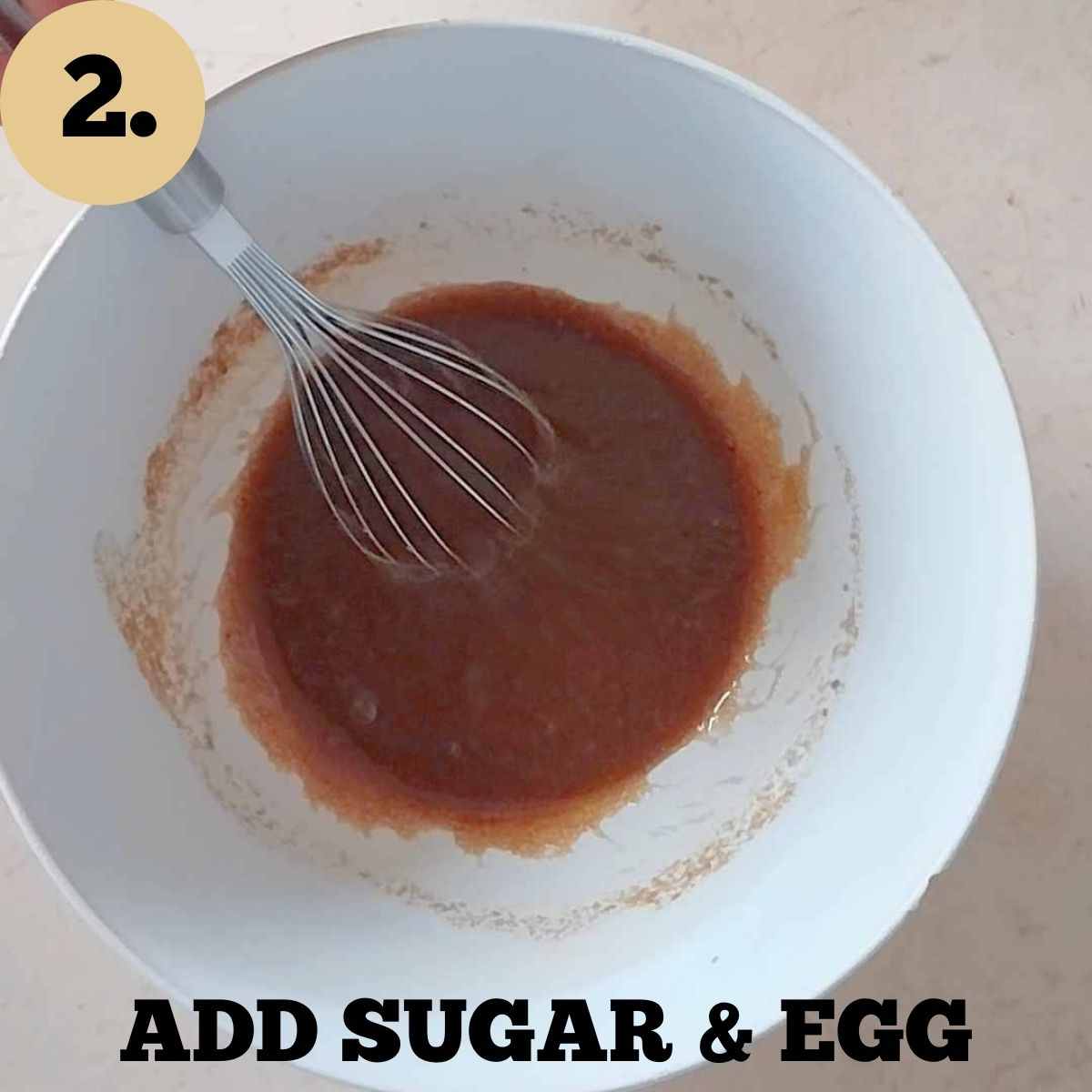 A white mixing bowl with mixed sugar, butter, and egg.