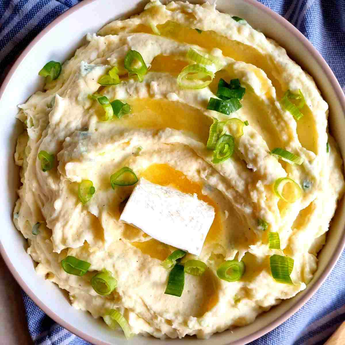 Mashed potatoes with chopped green onion and butter on top.