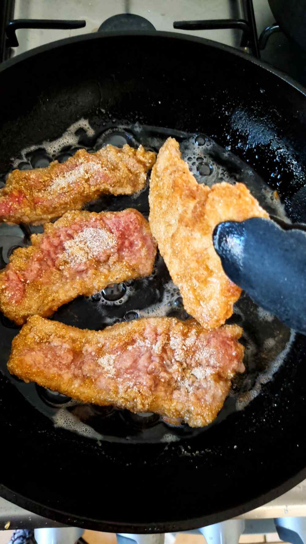 Flipping the pork cutlets in the frying pan.
