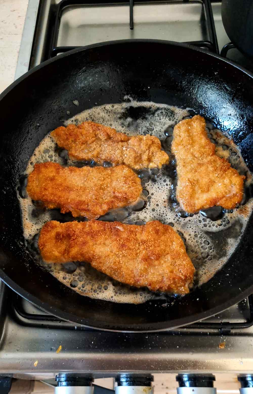 Frying the breaded pork cutlets on the other side.