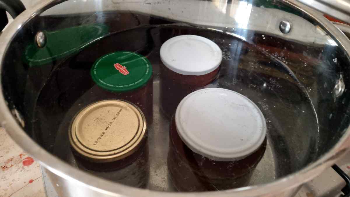 Jam cans in a large pot covered in water for water bath canning.