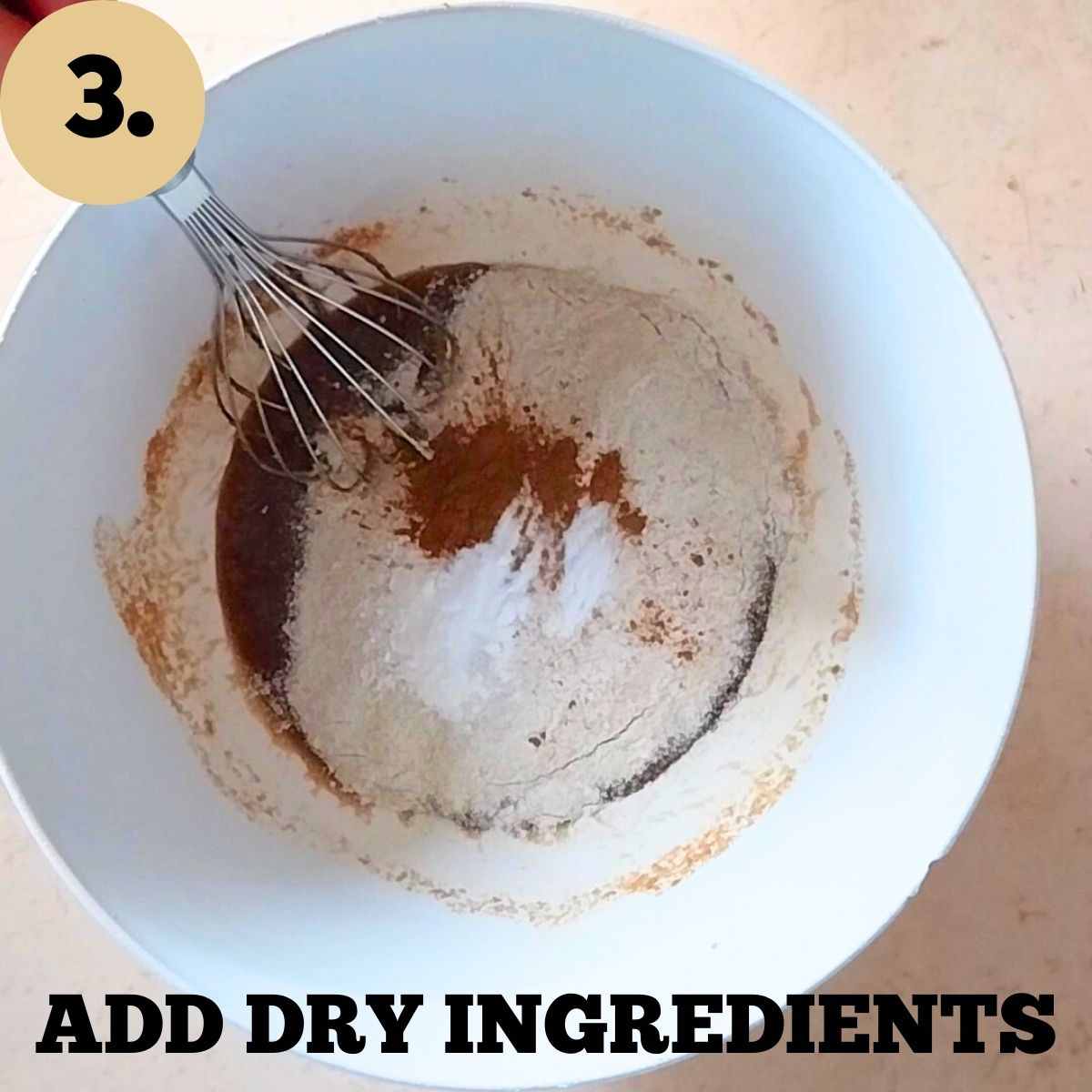A mixing bowl with added dry ingredients and a whisk.