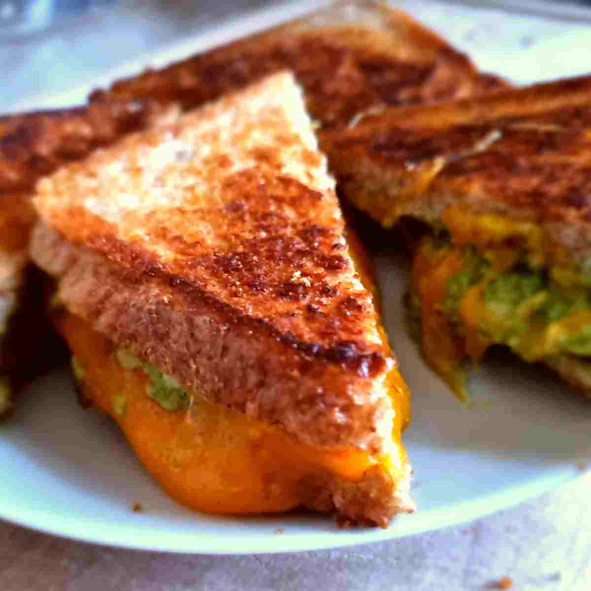 Avocado grilled cheese sandwiches cut into triangles on a white plate.
