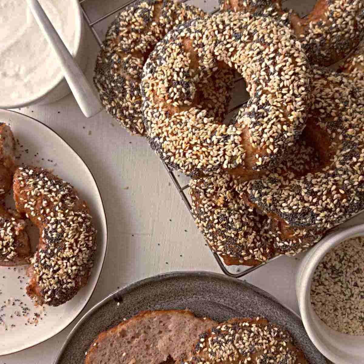 Gluten-free sourdough discard bagels on a table with plates and cream.