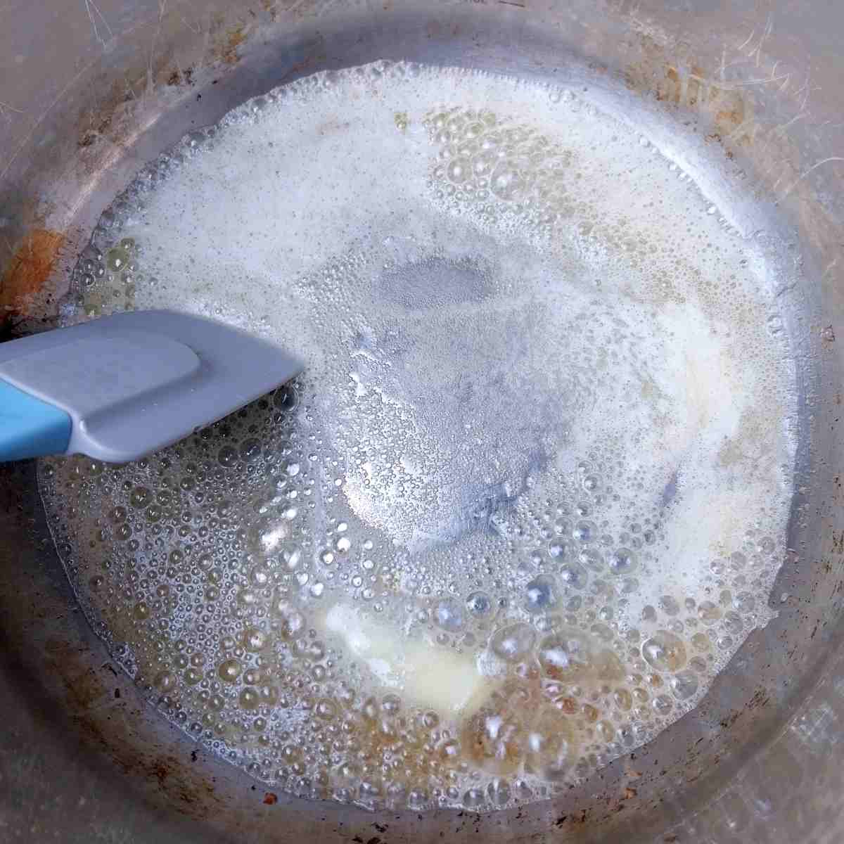 Melting butter in the pot with a spatula stirring.