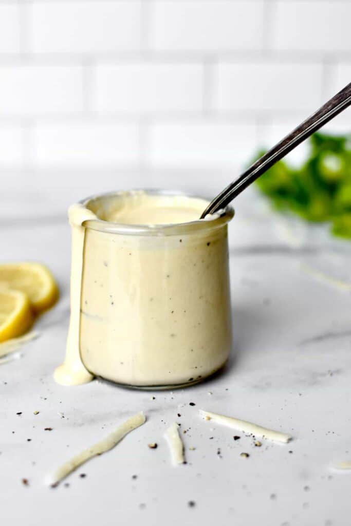 Greek yoghurt dressing in a jar with a spoon.