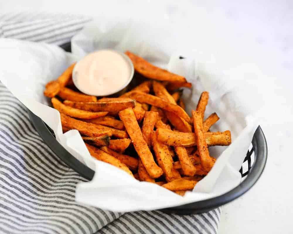 Sweet potato fries with white sauce on a serving platter.