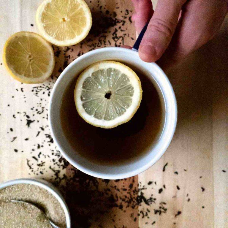 A cup of tea with a lemon on top.