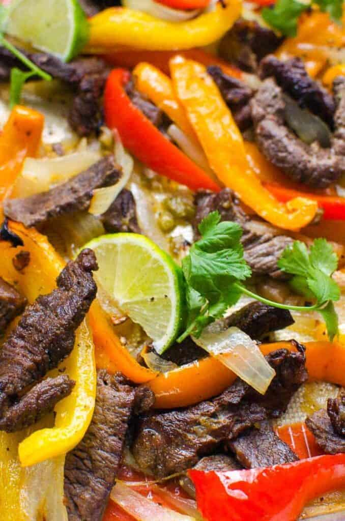 Peppers, lime, steak stripes on a sheet pan close up.