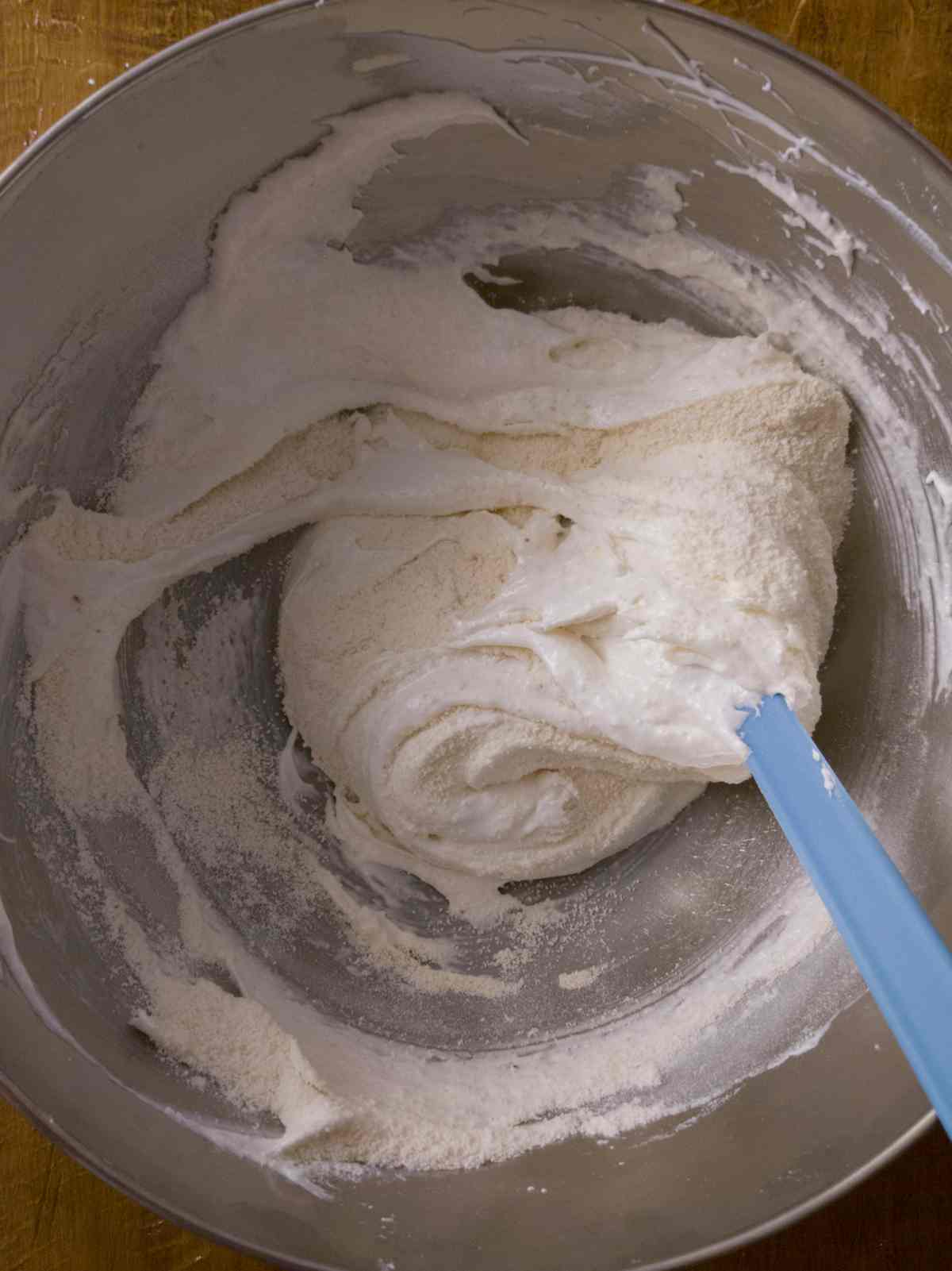 Folding flour into the egg whites with a rubber spatula.