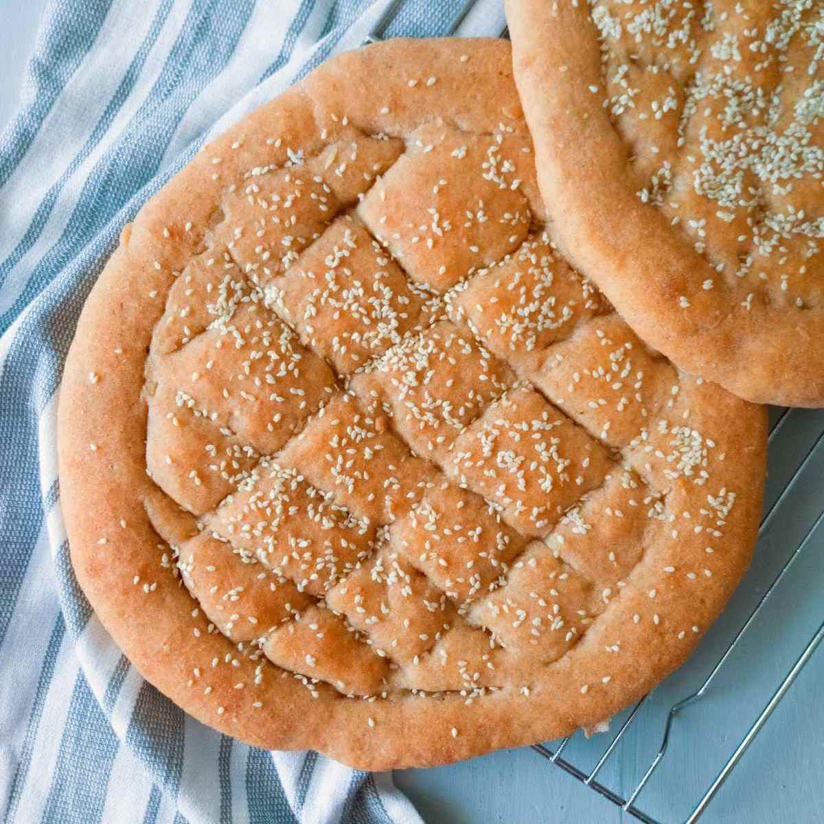 Gluten-free Turkish bread on a cooling rack with a kitchen towel next to it.