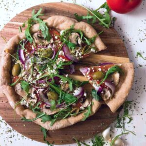 Gluten-free sourdough pizza with a piece cut out.