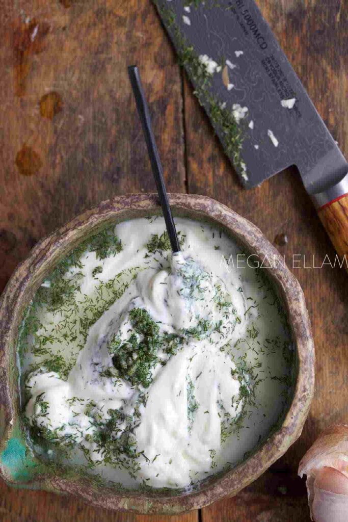 Kebab sauce in a wooden bowl with a knife in the background.