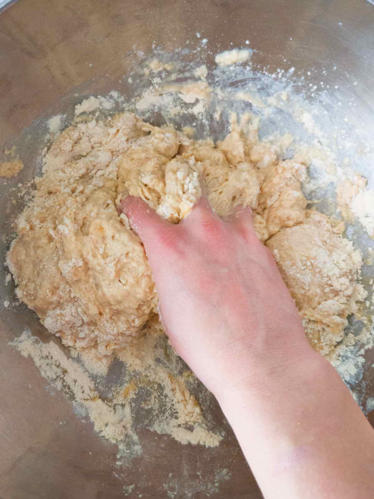 Mixing the dough by hand in a large metal bowl.