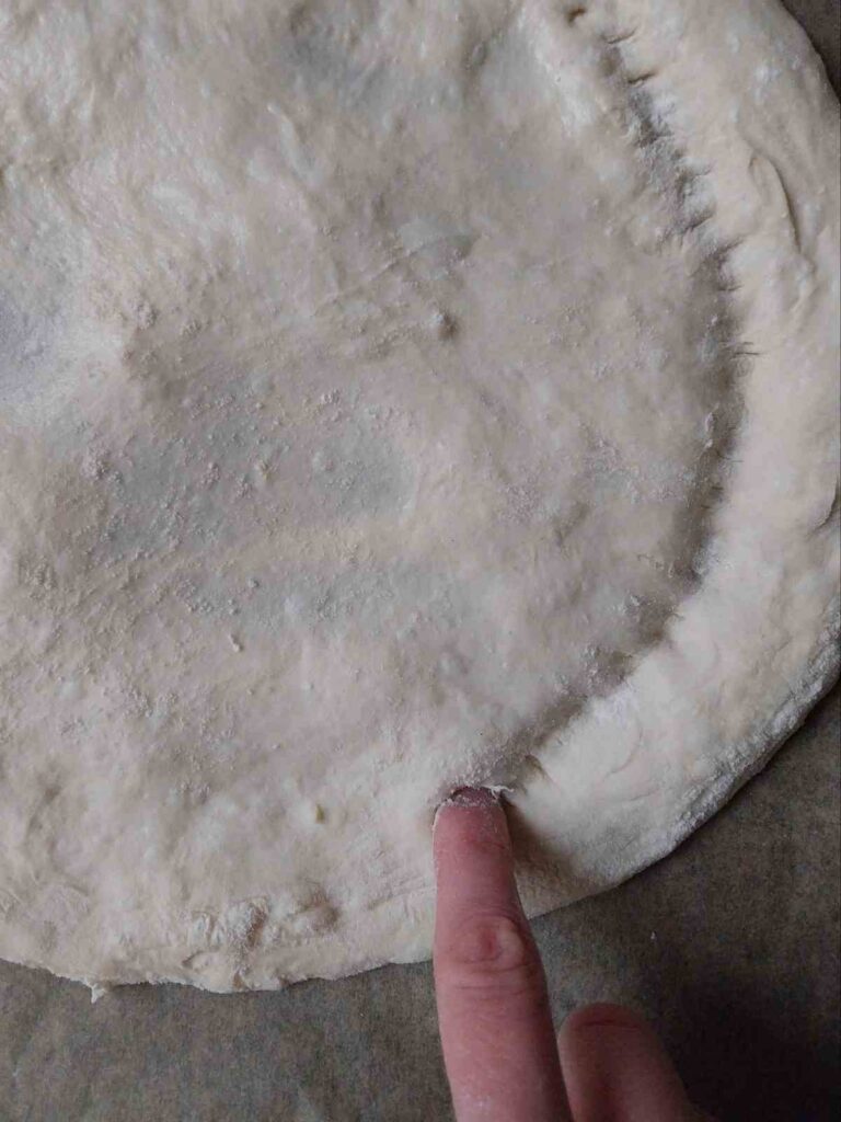 Poking holes in the flatbread with a finger.