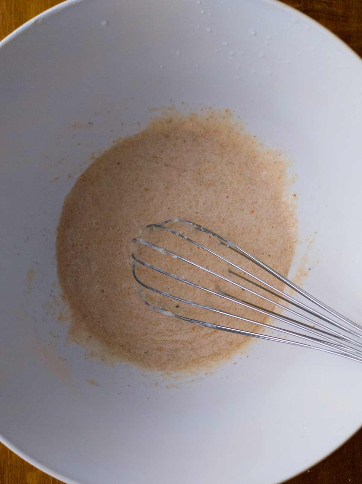 Psyllium husk and sourdough starter in a mixing bowl with a whisk. 