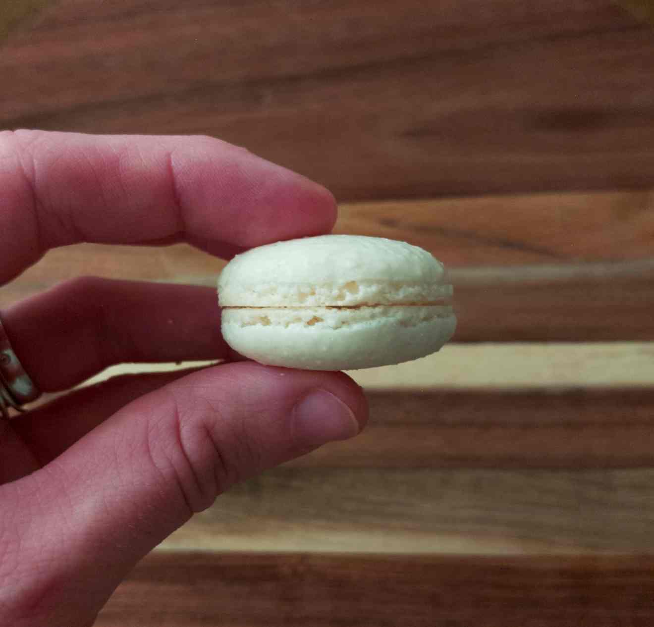 Baked macaron shells in held by a hand.