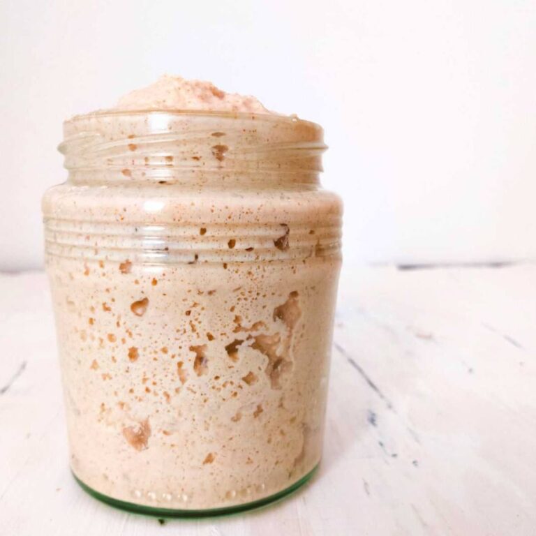 Gluten-free sourdough starter in a glass jar up close.