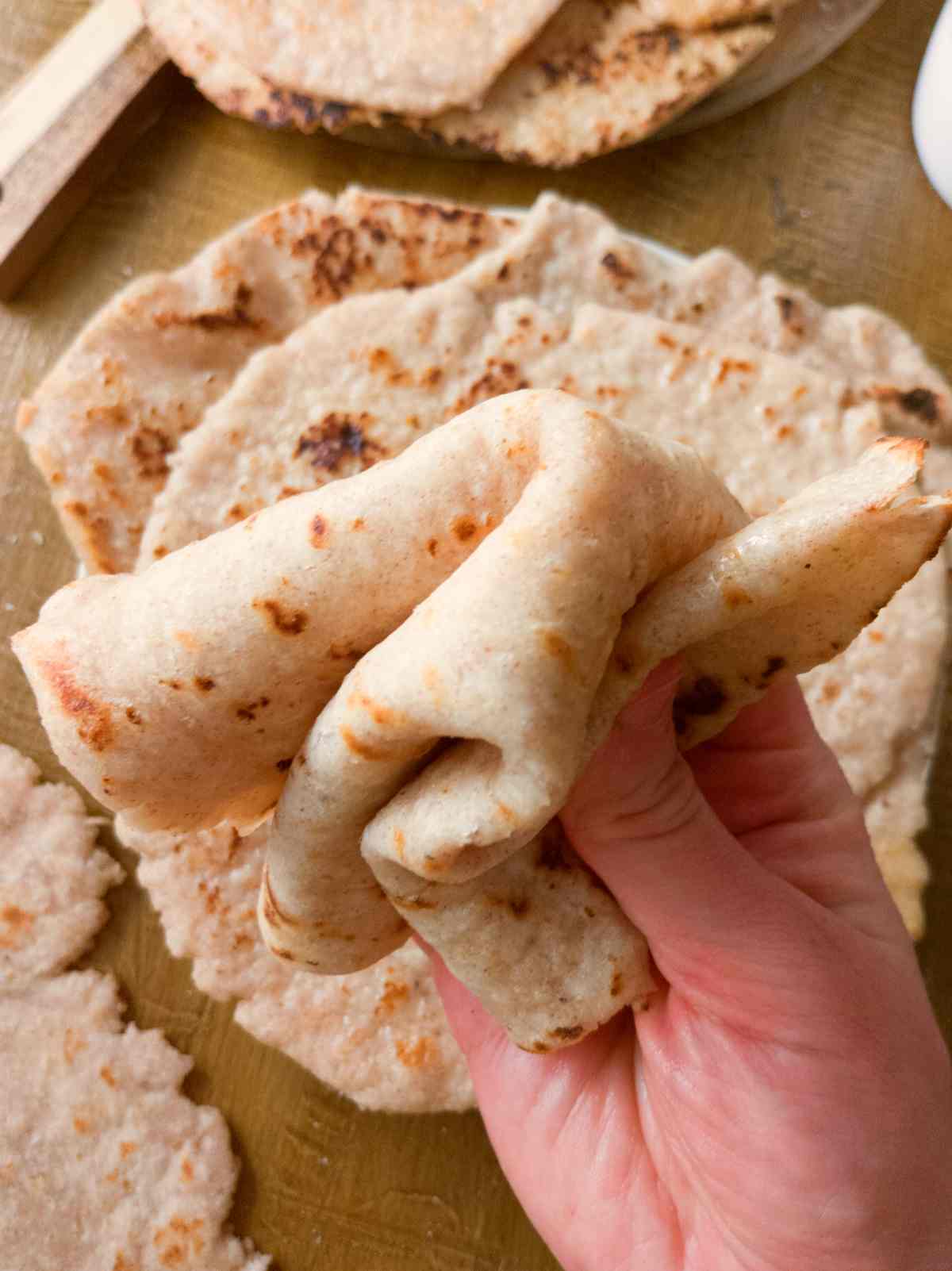 Gluten-free sourdough flatbread bent in a hand.
