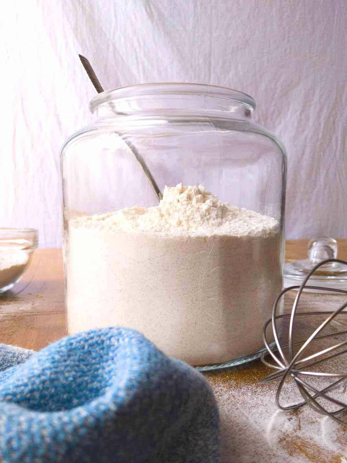 Mixing flours in a large jar with a spoon.