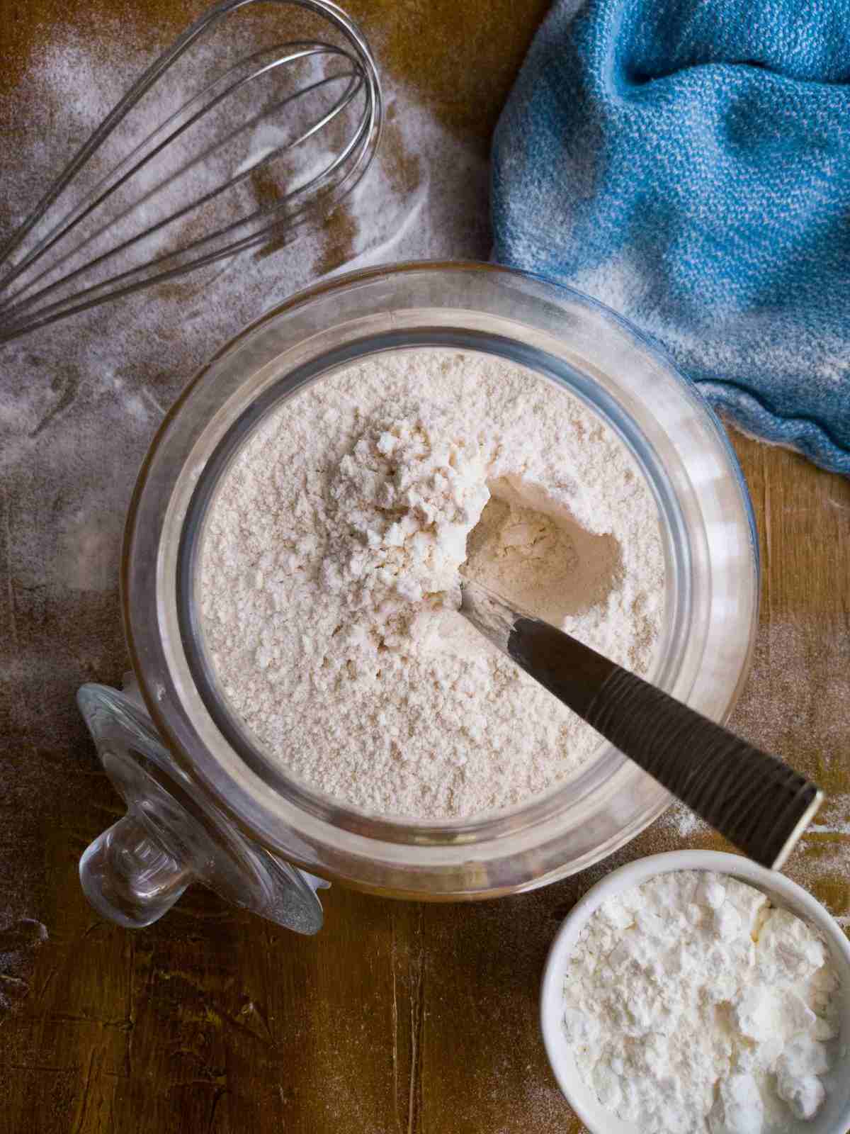 Flour in a large glass jar with a spoon sticking out of it.